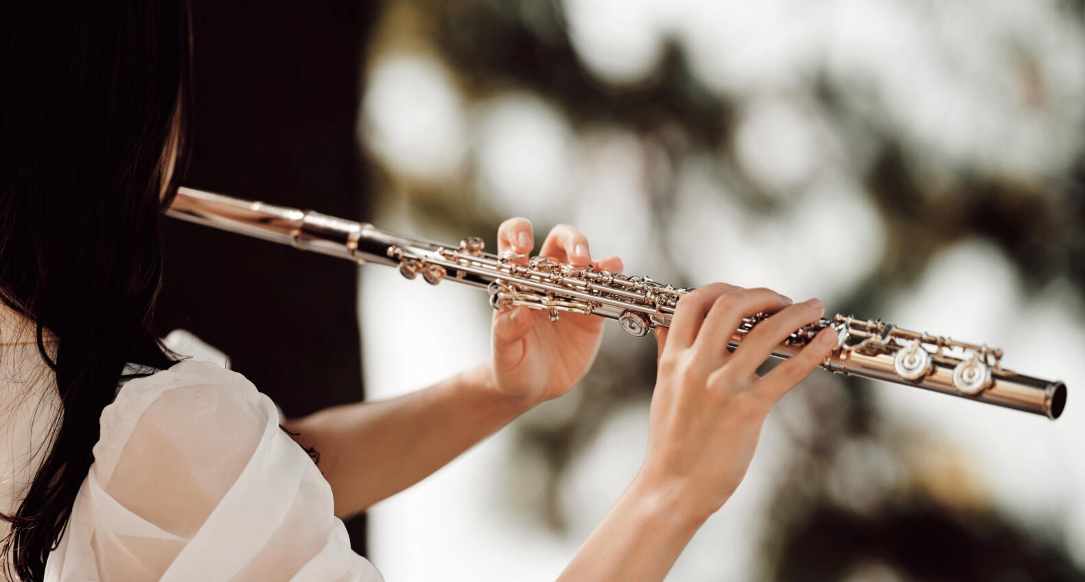 Young girl playing flute outdoors.